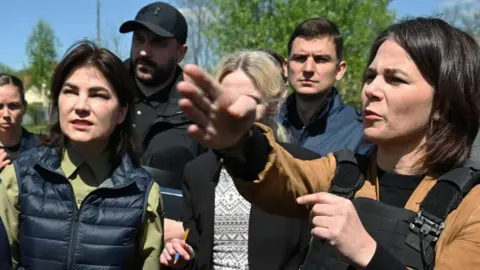 Getty Images German Foreign Minister Annalena Baerbock (R) and Ukraine's Prosecutor General Iryna Venediktova (L) attend outside St. Andrew and Pyervozvannoho All Saints church at the former mass grave of civilian people in Bucha, northwest of Kyiv, on May 10, 2022