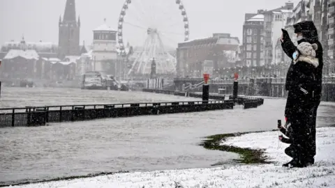 EPA People walk along the Rhine promenade during the snowfall