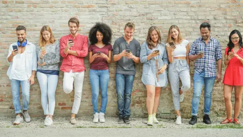 Getty Images People in a line with mobile phones