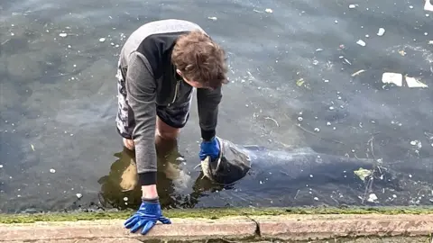 A man pulls a large fish from the River Seine in Paris, France