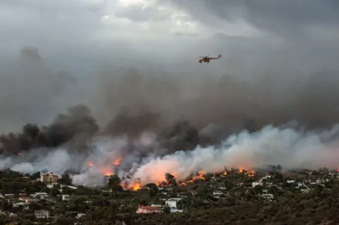 AFP A firefighting helicopter flies over a wildfire raging in the town of Rafina