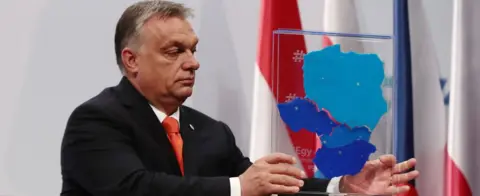 Getty Images Hungarian Prime Minister Viktor Orban lifts a box depicting the V4 member countries on 21 June