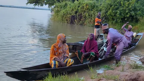 BBC/ Ahmed Ambali People in a wooden boat