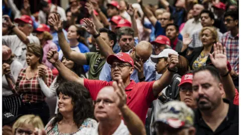 Getty Images Attendees pray together before President Donald Trump addresses the crowd at the King Jesus International Ministry during a "Evangelicals for Trump" rally in Miami