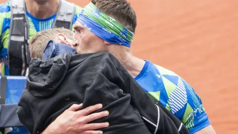 Danny Lawson / PA Media Kevin Sinfield kissing Rob Burrow on the cheek as they cross the finish line