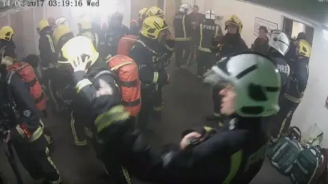 Grenfell Tower Inquiry Glynn Williams (top right) pointing at a wall on the ground floor of Grenfell Tower on 14 June 2018