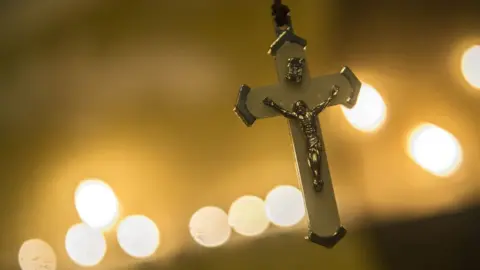 AFP A crucifix hangs in front of candles as Egyptians attend a candlelit vigil on 17 December 2016