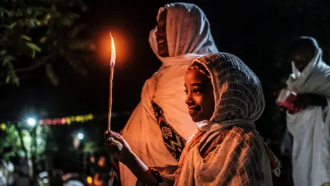 AFP A woman and girl holding at candle at the Fasilides Bath during Timket in Gondar, Ethiopia - Wednesday 19 January 2022