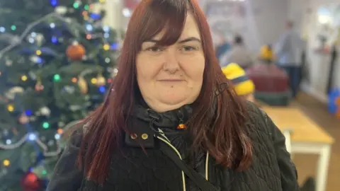 BBC Woman at charity hub with Christmas decorations in the background