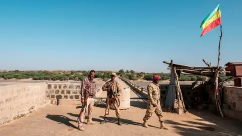 Getty Images Two members of the Amhara Special Forces with a member of the Amhara militia (L) stand at the border crossing with Eritrea where an Imperial Ethiopian flag waves, in Humera, Ethiopia, on November 22, 2020.