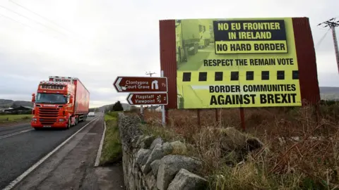 AFP File image of traffic crossing the border into Northern Ireland from the Irish Republic past a Brexit Border poster on December 1, 2017