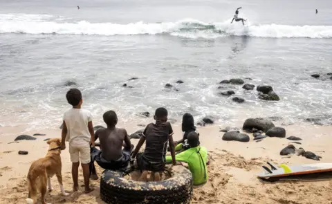 AFP Children look on at a surfer in Dakar, Senegal - Sunday 6 March 2022