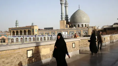 Reuters File photo showing people walking past the shrine of Fatima Masumeh in Qom, Iran (9 February 2020)