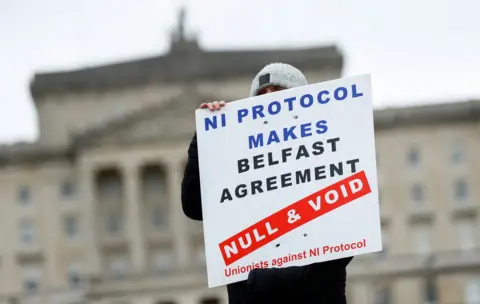 Pacemaker A loyalist protester at Stormont holds a sign that reads: NI Protocol makes Belfast Agreement null and void - unionists against NI Protocol