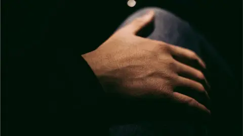 Getty Images A hand on a knee in the dark
