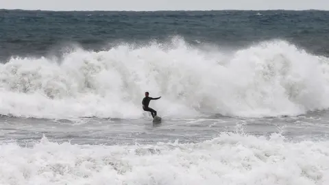 EPA A surfer takes advantage of the big waves breaking at Barceloneta beach in Barcelona, Spain