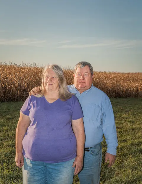 Ian Brown Art Tanderup and a woman standing next to a field of crops