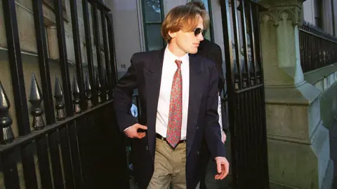 Getty Images A man in a suit and sunglasses leaves court