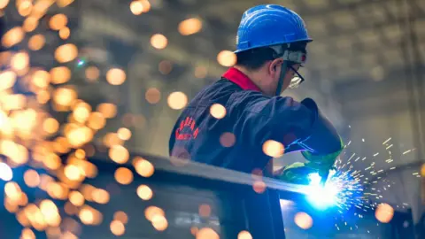 Getty Images A worker welds at a temperature control equipment manufacturing enterprise in Qingzhou Economic Development Zone, East China's Shandong province.