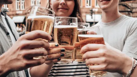 Getty Images Four friends having a drink of beer