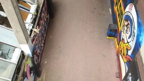 West Northamptonshire Council Part of walkway, showing graffiti and broken windows