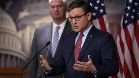 Getty Images : U.S. Speaker of the House Rep. Mike Johnson (R-LA) (R) speaks as House Majority Whip Rep. Tom Emmer (R-MN) (L) listens during a news briefing at the U.S. Capitol on November 2, 2023 in Washington, DC. House Republican held a Conference meeting to discuss party agenda.