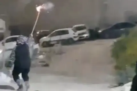 BBC Rami Hamdan Al-Halhouli, 12, holds a firework aloft moments before being shot by Israeli police.