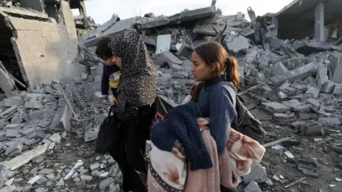 Reuters Palestinians walk past houses destroyed by Israeli air strikes in Rafah, southern Gaza Strip. Photo: 12 February 2024