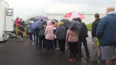 BBC People queuing for TB screening session in Llwynhendy