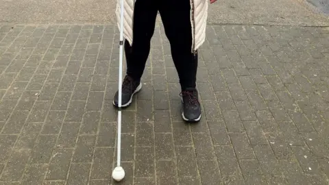 A person holding a white cane on a street