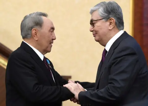 Reuters Acting President of Kazakhstan Kassym-Jomart Tokayev (R) shakes hands with his predecessor Nursultan Nazarbayev