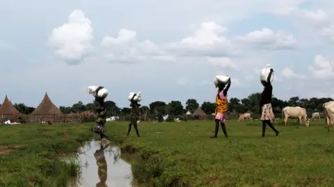 Reuters Displaced women carry food from a distribution centre near the town of Nyal - 29 October