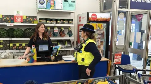 Cambridgeshire Constabulary PCSO talking to staff at The Factory Shop, Whittlesey