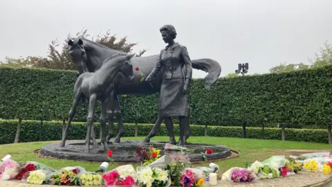 Rachael McMenemy/BBC Flowers laid at the statue of the Queen in Newmarket