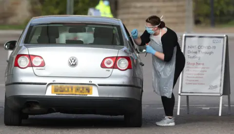 PA Media Medical staff testing people at a drive-through centre