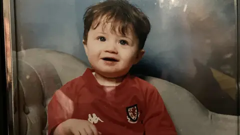 Family photo Neco Williams as a baby, wearing a Wales kit