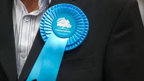 Getty Images A man wearing a Conservative rosette