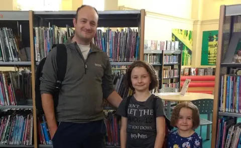 Father and daughters in library