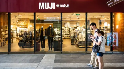 Getty Images Pedestrians walk past a Japanese household and consumer goods retailer, Muji store in Shenzhen