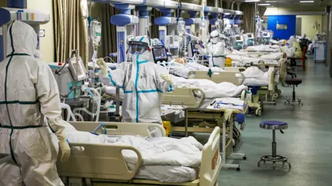 Reuters Medical workers in protective suits with Covid-19 patients in Wuhan, China, 6 February 2020