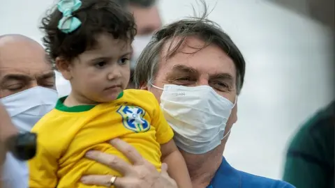 EPA Brazilian President Jair Bolsonaro lifts up a girl during a rally with supporters in Brasilia, 17 May 2020