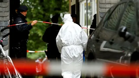 Reuters Police officers at the entrance of a residential building where the bodies of five children were found in the western town of Solingen, Germany