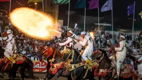 Fadel Senna/Getty Men on horses shooting rifles in celebration, 6 August 2023