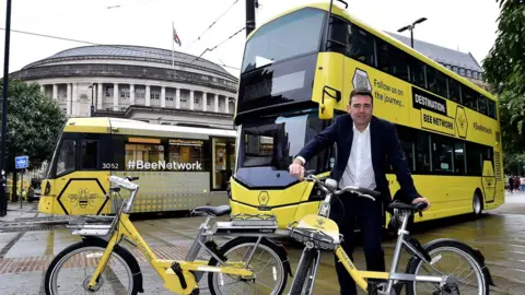 TFGM Andy Burnham with Bee Network bikes, bus and tram outside the Central Library in Manchester