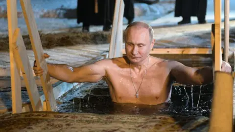 ALEXEY DRUZHININ/AFP Vladimir Putin plunges into icy waters to celebrate the Epiphany holiday in January