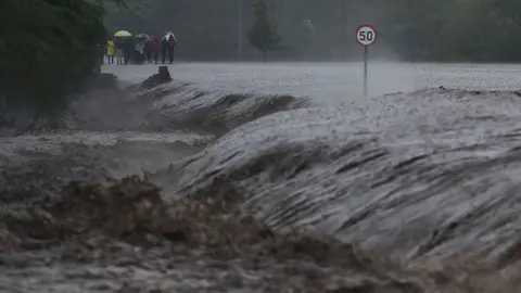 AFP People watch as flash floods rage past a part of the main highway to Kenya"s border town with Tanzania on March 15, 2018 in Isinya, Kajiado county, around 58 kilometres (36 miles) southeast of capital Nairobi.