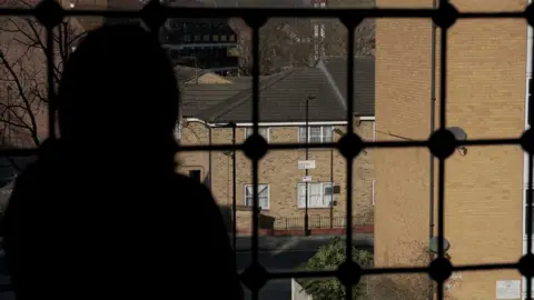 Suri, seen in silhouette, looking over Hackney