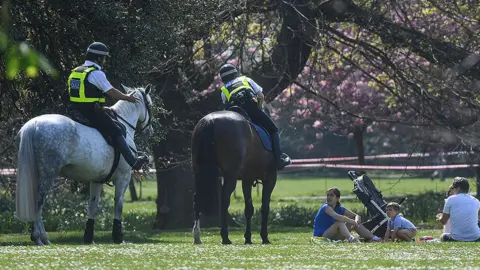 Getty Images Police on horses speaking to people having a picnic