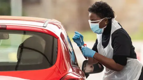 Getty Images nurse administering covid test to driver in car