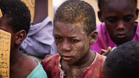 BBC Children huddled on the floor at a makeshift school